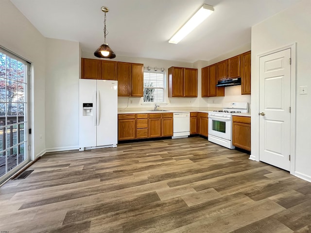 kitchen with decorative light fixtures, plenty of natural light, white appliances, and sink