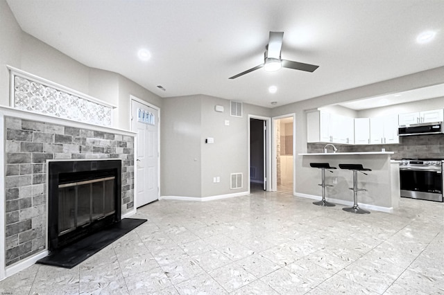 unfurnished living room featuring ceiling fan and a fireplace