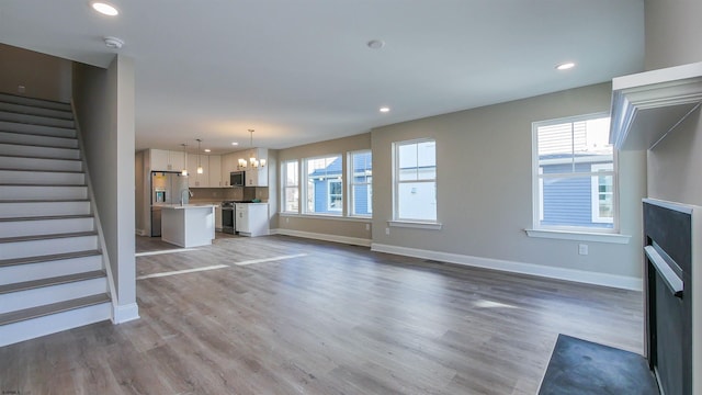 unfurnished living room with wood-type flooring and a chandelier