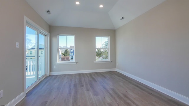 spare room with a healthy amount of sunlight, vaulted ceiling, and light hardwood / wood-style floors