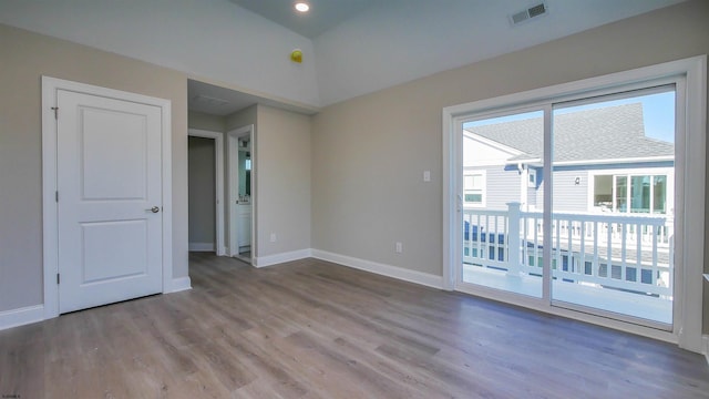 empty room with hardwood / wood-style floors and vaulted ceiling