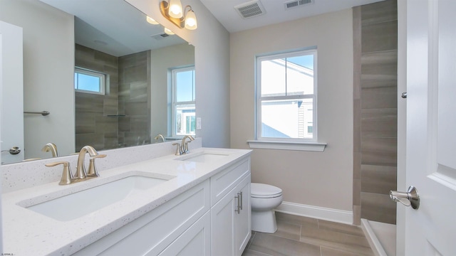 bathroom with vanity, toilet, and a tile shower