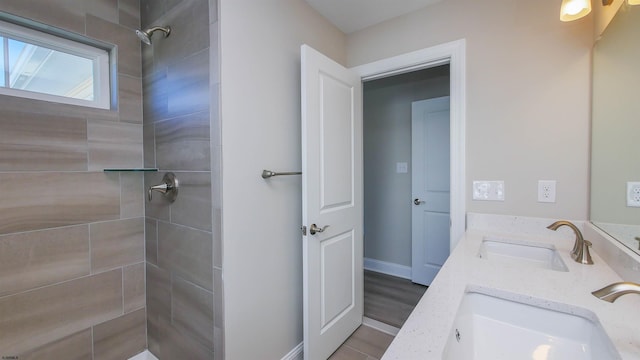 bathroom with tiled shower and vanity