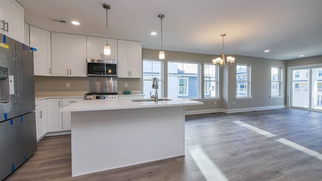 kitchen featuring white cabinets, stainless steel appliances, and an island with sink