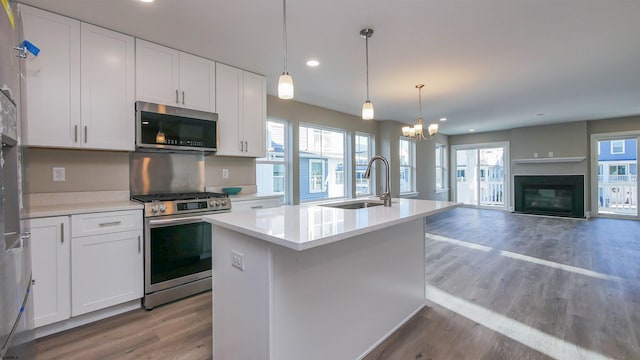 kitchen featuring sink, decorative light fixtures, a center island with sink, white cabinets, and appliances with stainless steel finishes