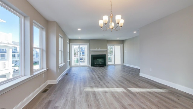 unfurnished living room with a chandelier and light wood-type flooring