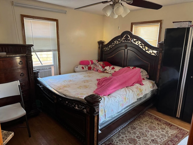 bedroom with black refrigerator, cooling unit, ceiling fan, and dark wood-type flooring