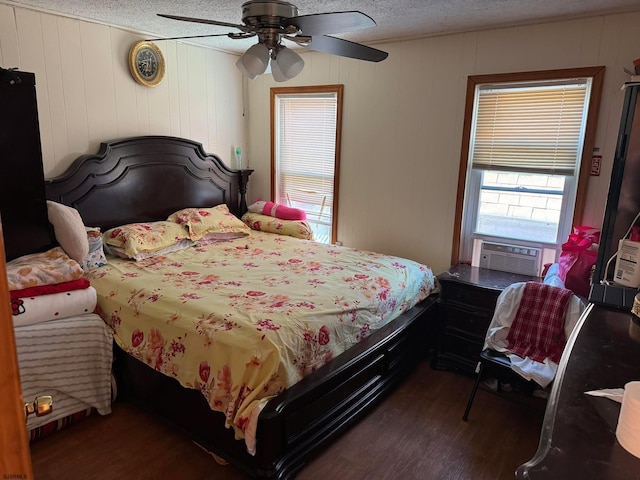 bedroom featuring ceiling fan, dark hardwood / wood-style flooring, a textured ceiling, and wooden walls