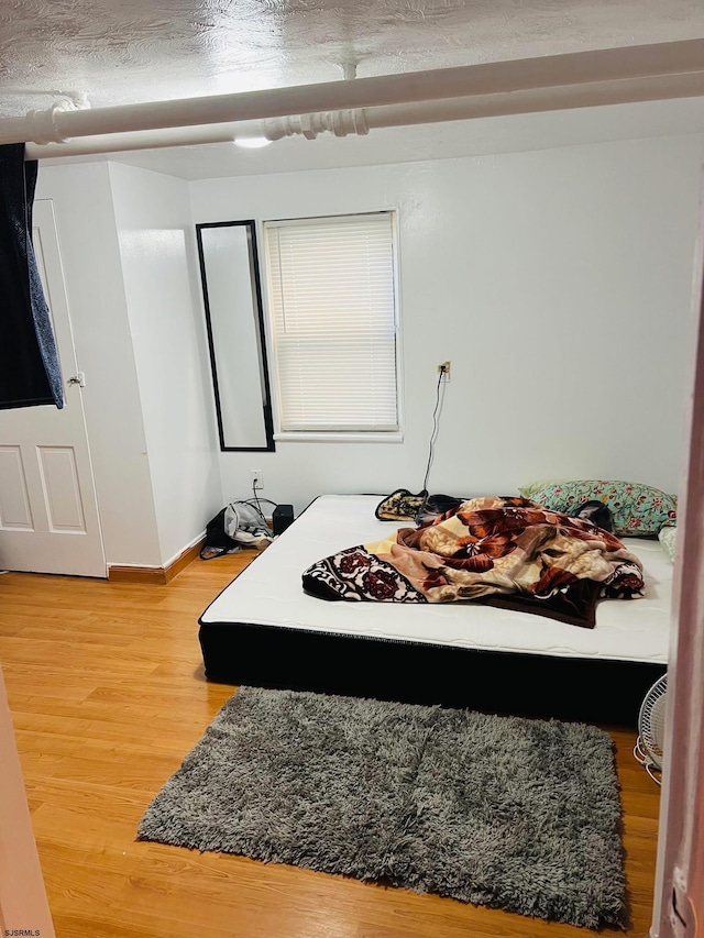 bedroom with hardwood / wood-style floors and a textured ceiling