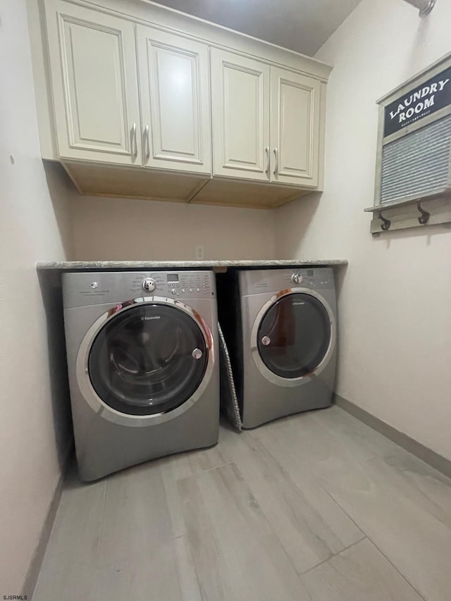 clothes washing area featuring washer and dryer, cabinets, and light hardwood / wood-style flooring