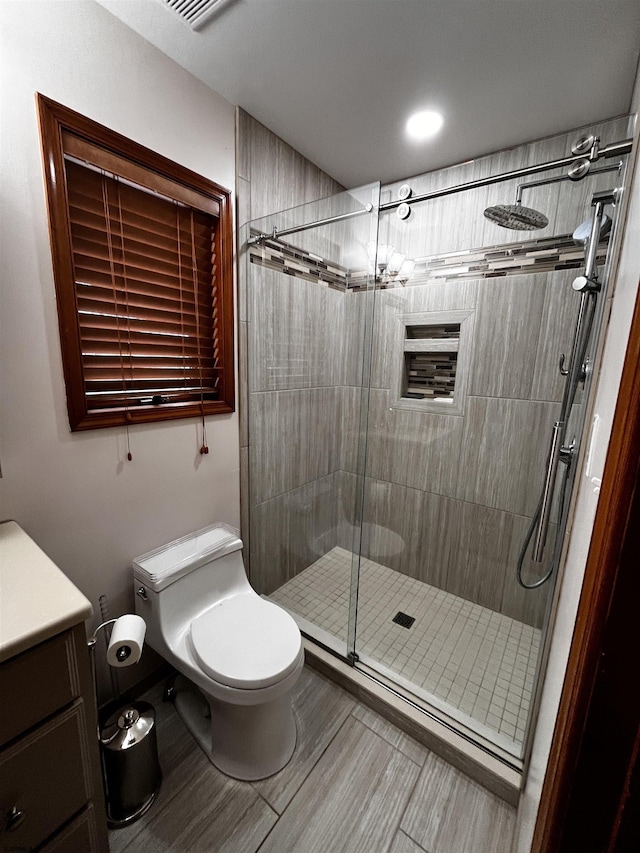 bathroom featuring vanity, toilet, and a shower with door