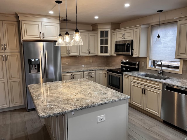 kitchen featuring decorative light fixtures, stainless steel appliances, a kitchen island, and sink