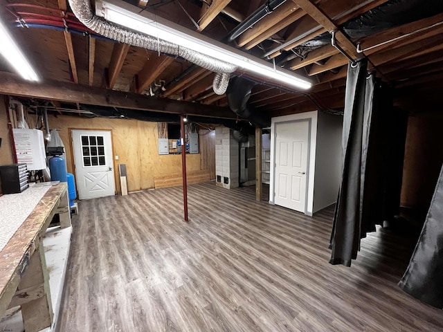 basement with hardwood / wood-style flooring, electric panel, and wooden walls