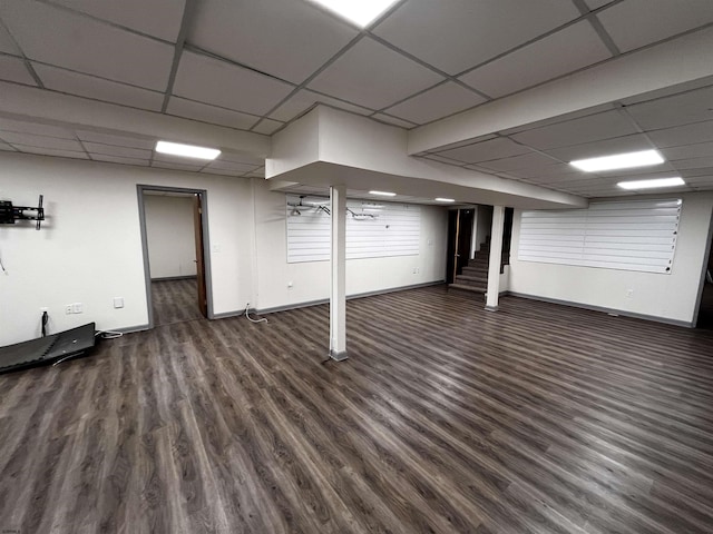 basement featuring a paneled ceiling and dark wood-type flooring