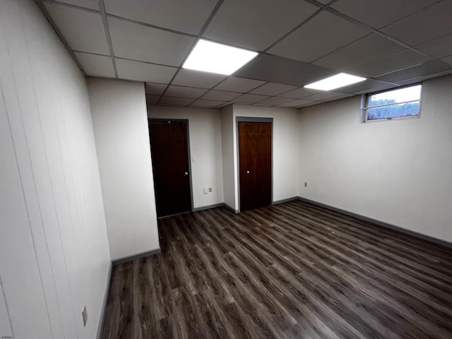 empty room with a paneled ceiling and dark hardwood / wood-style flooring