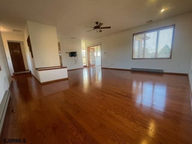 unfurnished living room featuring baseboard heating, ceiling fan, and dark hardwood / wood-style flooring