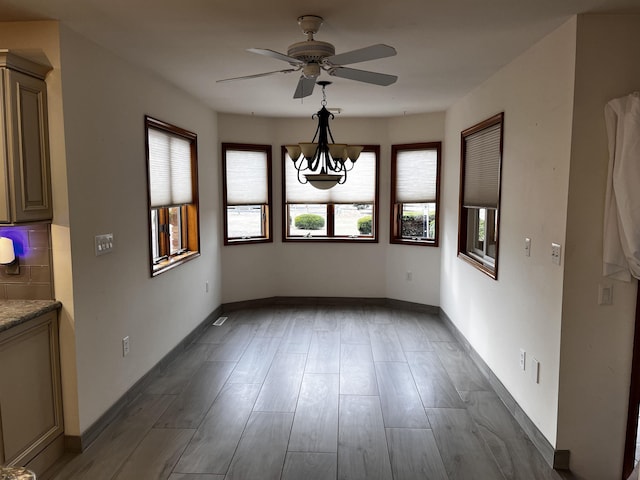 unfurnished dining area with ceiling fan with notable chandelier and dark hardwood / wood-style flooring