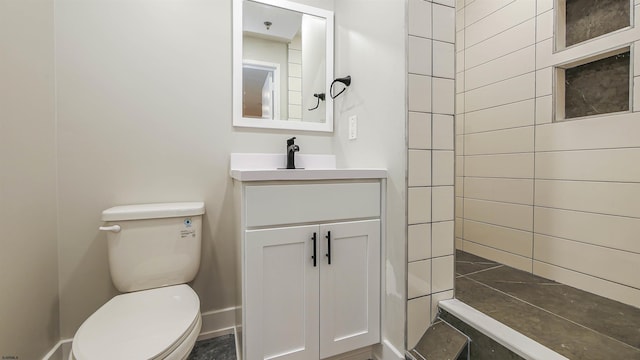 bathroom with vanity, toilet, and a tile shower