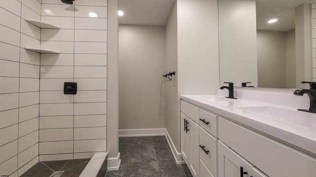 bathroom with a tile shower and vanity