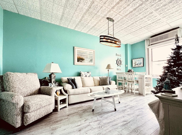 living room with a wall mounted AC, hardwood / wood-style floors, and an inviting chandelier