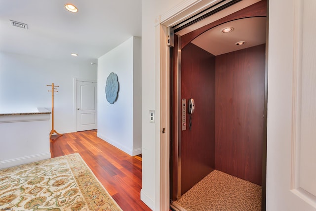 hall with elevator and hardwood / wood-style flooring