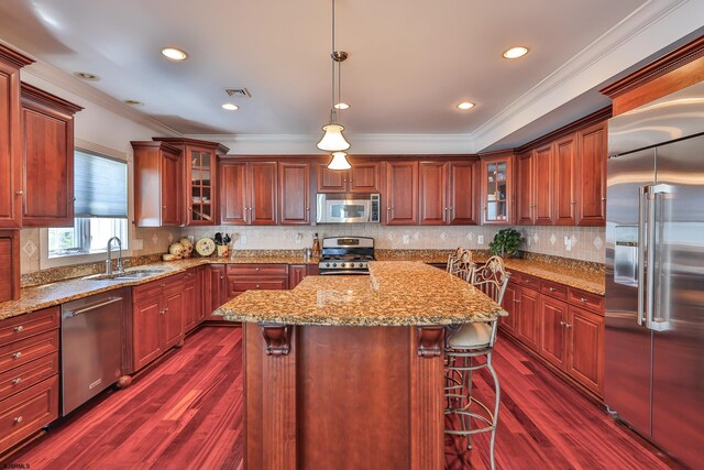 kitchen featuring pendant lighting, a center island, sink, dark hardwood / wood-style floors, and stainless steel appliances