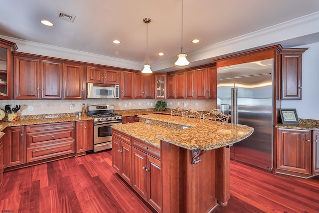 kitchen featuring pendant lighting, a kitchen breakfast bar, appliances with stainless steel finishes, a kitchen island, and dark hardwood / wood-style flooring