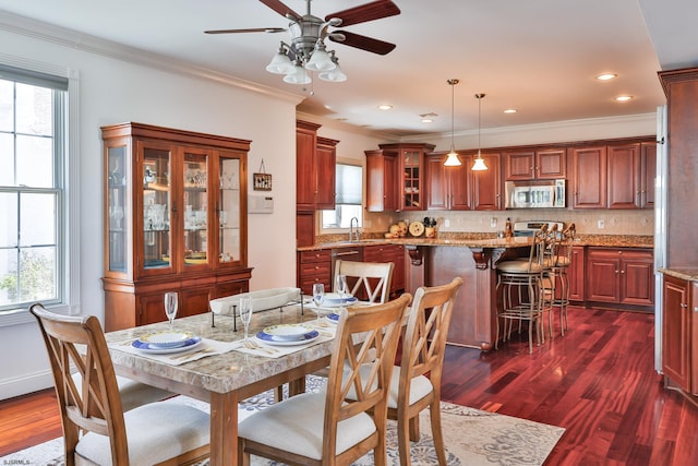 dining space with dark hardwood / wood-style floors, a wealth of natural light, crown molding, and sink