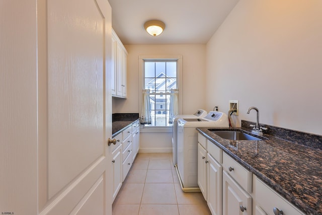 kitchen featuring white cabinets, sink, dark stone countertops, washing machine and dryer, and light tile patterned floors