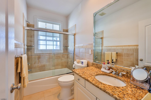 full bathroom with vanity, tile patterned floors, toilet, enclosed tub / shower combo, and tile walls