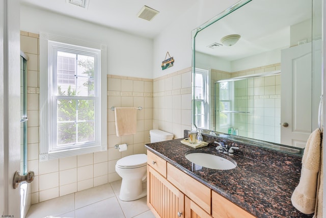 bathroom with vanity, tile patterned floors, toilet, tile walls, and walk in shower