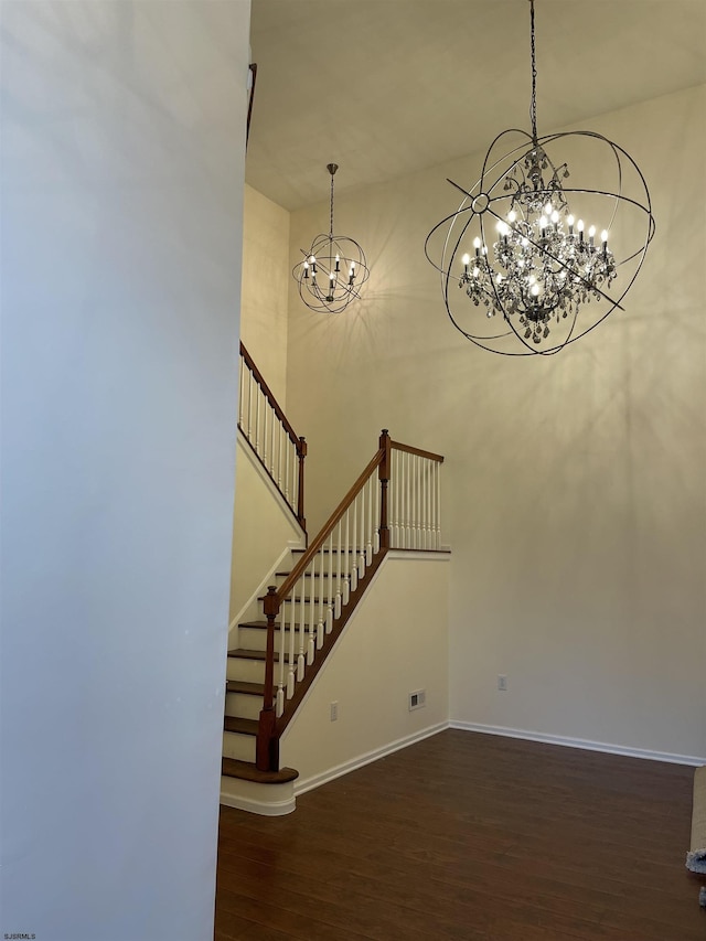 stairs with wood-type flooring and an inviting chandelier