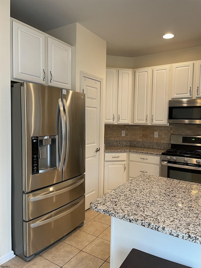 kitchen with light stone countertops, white cabinetry, and stainless steel appliances