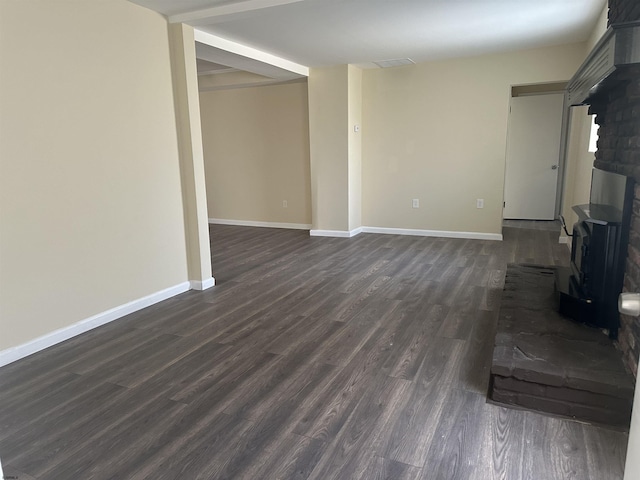 unfurnished living room with dark hardwood / wood-style flooring and a wood stove