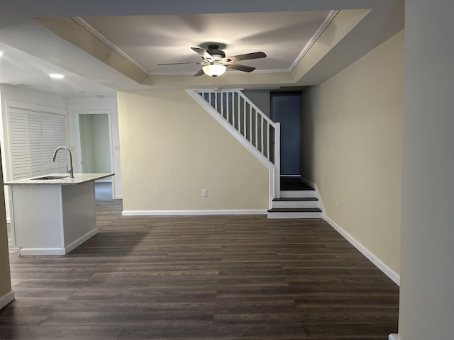 unfurnished living room with a tray ceiling, sink, dark wood-type flooring, and ornamental molding