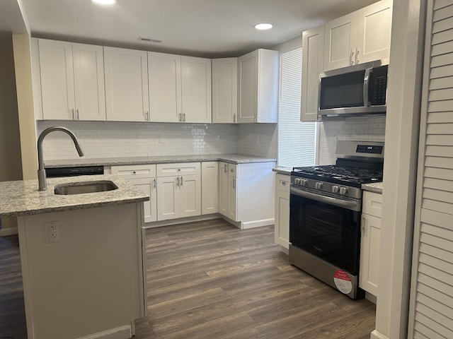 kitchen with white cabinetry, an island with sink, stainless steel appliances, and light stone counters