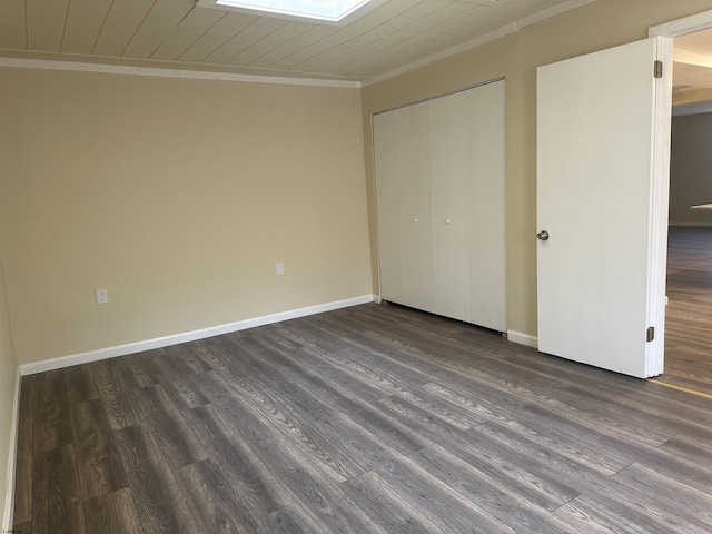 unfurnished bedroom with a closet, crown molding, dark hardwood / wood-style flooring, and wooden ceiling