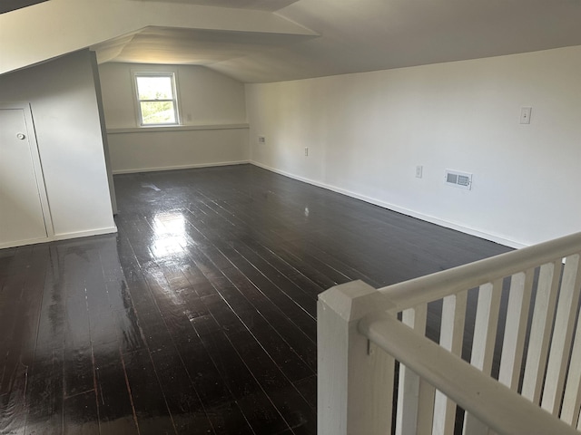 bonus room with vaulted ceiling and dark wood-type flooring