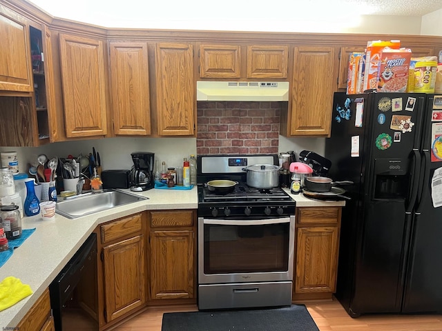 kitchen featuring black appliances, sink, and light hardwood / wood-style flooring