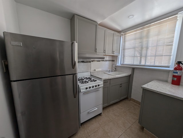 kitchen featuring gray cabinetry, stainless steel fridge, sink, and white range