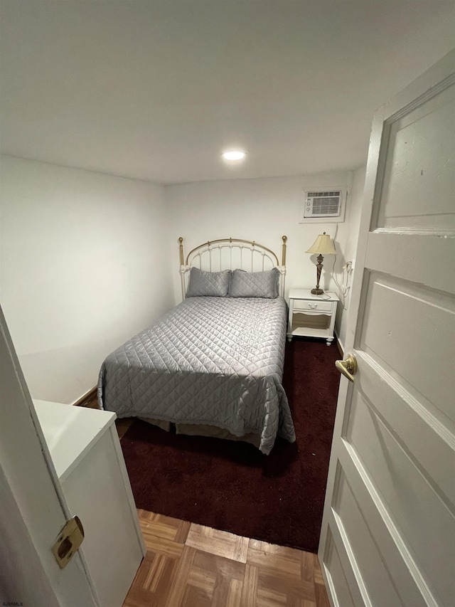 bedroom featuring a wall unit AC and parquet flooring