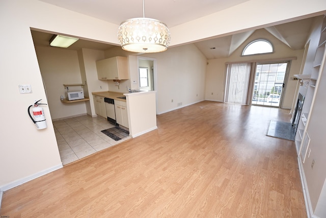 kitchen with vaulted ceiling with beams, decorative light fixtures, white appliances, and light wood-type flooring