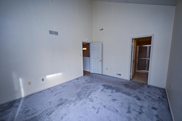 carpeted empty room with a high ceiling