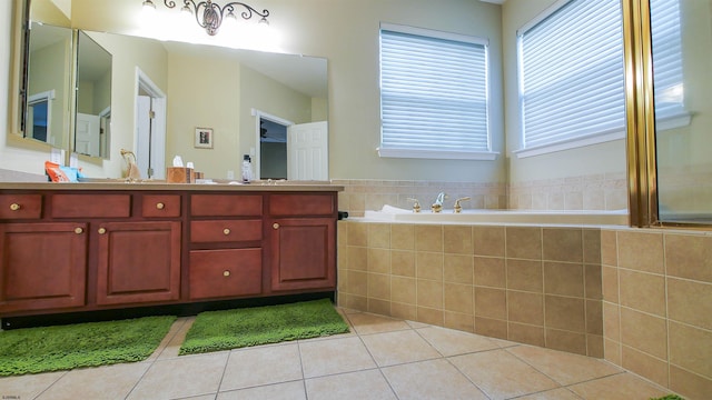 bathroom with tile patterned floors, vanity, and a relaxing tiled tub