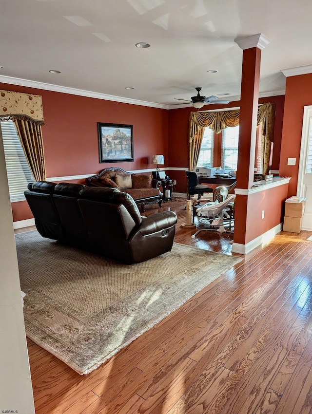 living room with decorative columns, ceiling fan, ornamental molding, and light wood-type flooring