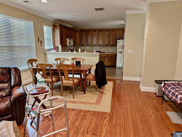 dining area with light wood-type flooring and ornamental molding