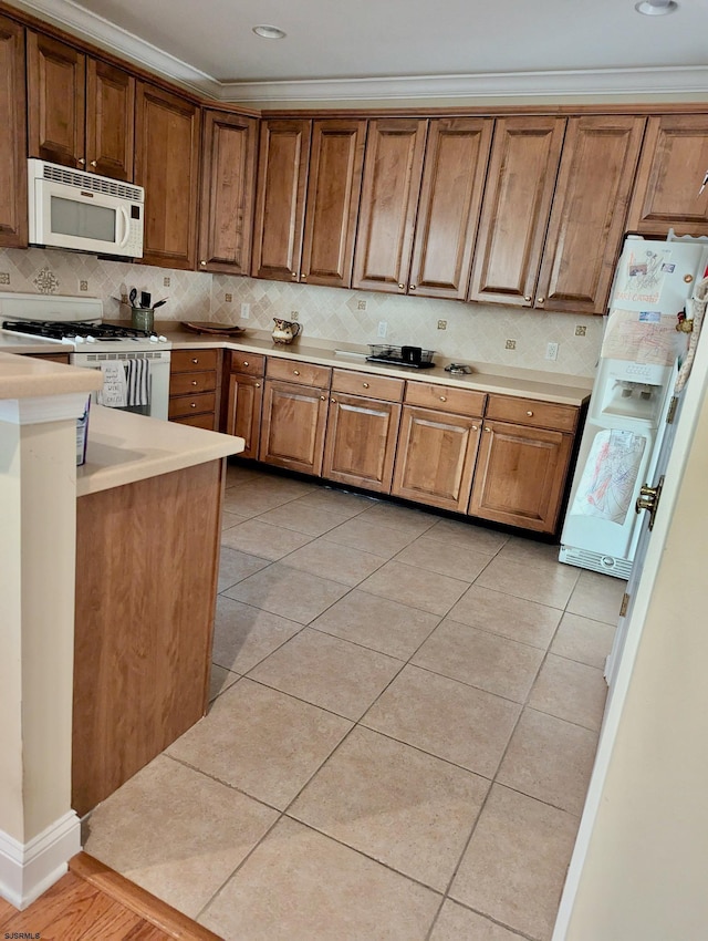 kitchen with crown molding, light tile patterned floors, and white appliances