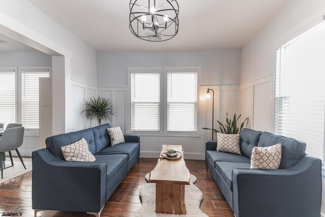 living room with dark wood-type flooring and a notable chandelier