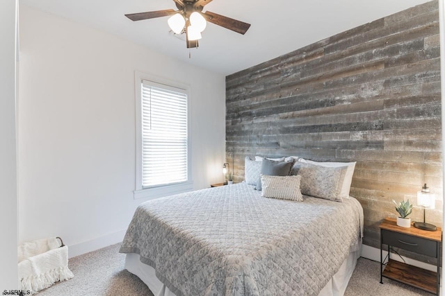 carpeted bedroom with ceiling fan and wood walls