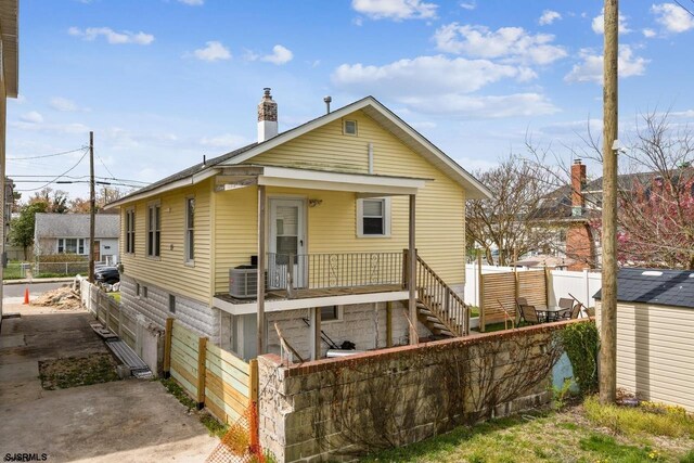 rear view of property featuring central AC and a shed